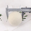 Set of wool laundry drying balls next to cotton storage bag for tumble dryers