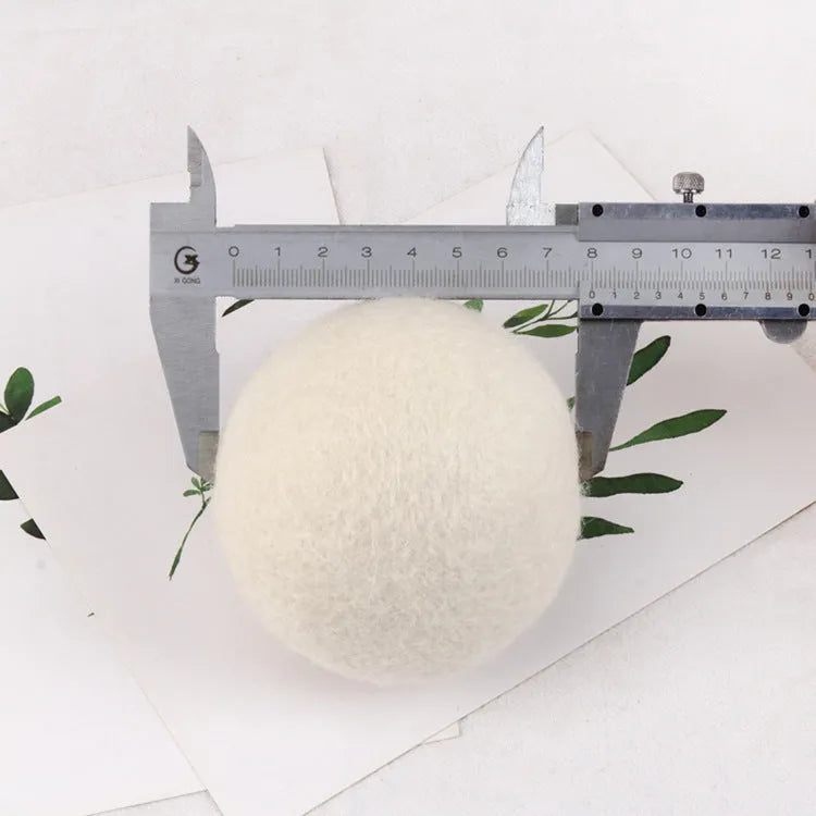 Set of wool laundry drying balls next to cotton storage bag for tumble dryers