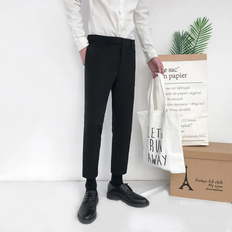 Man wearing black straight-leg cotton trousers with a drawstring waist, styled casually.