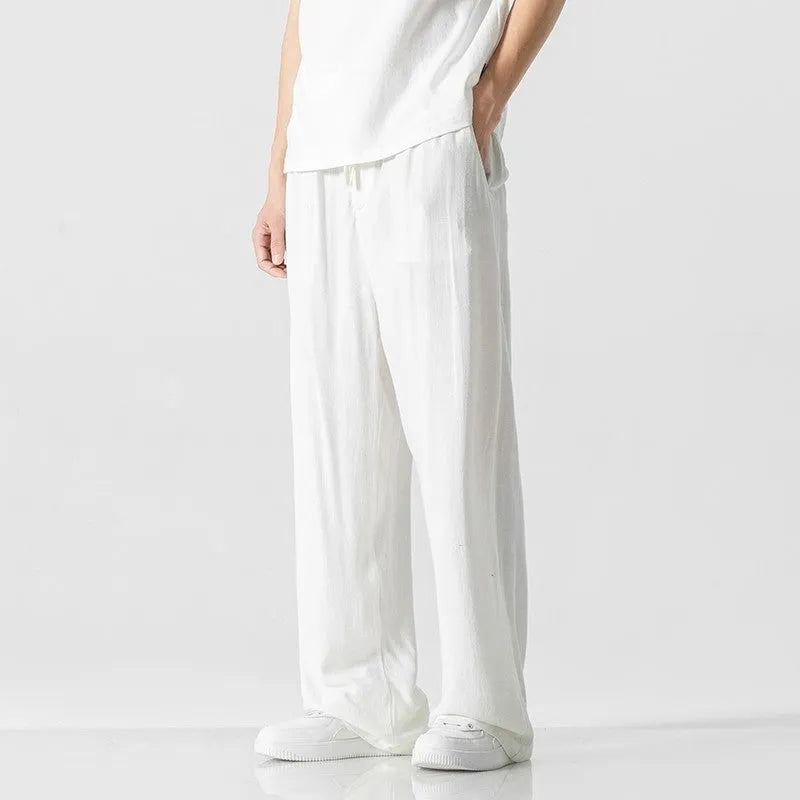 Man wearing beige loose-fit cropped straight-leg trousers made from bamboo fibre with a drawstring waist.