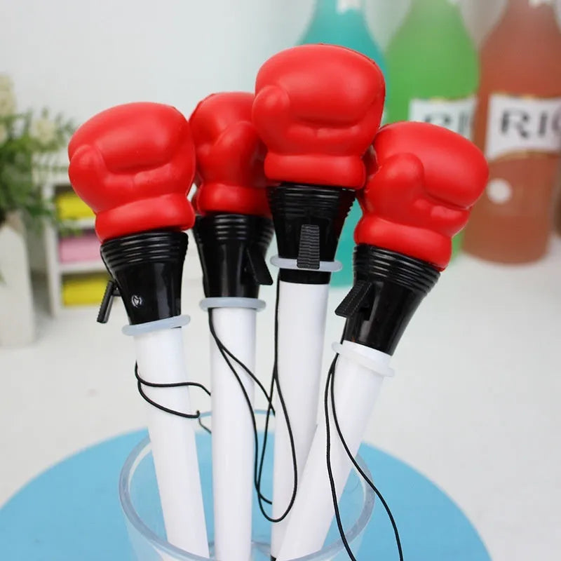 Set of four black pressure relief pens with a boxing press ejection mechanism on a desk.