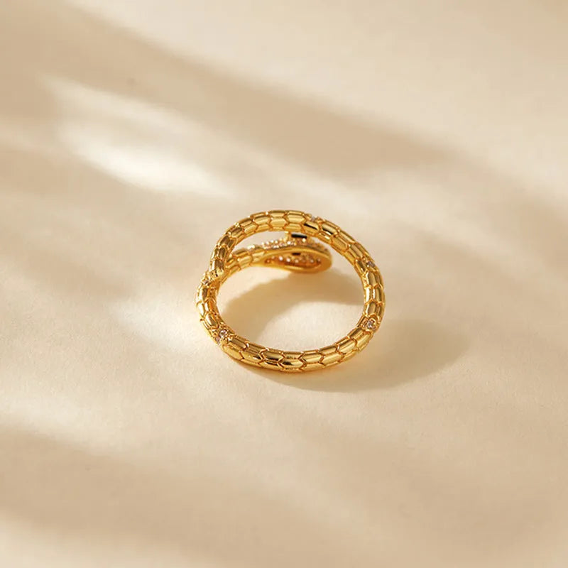 Snake-shaped adjustable copper ring with gold colour finish on a model's index finger.