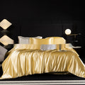 Silk bed sheet four-piece set in a solid colour displayed on a bed, showing fitted sheet and pillowcases.