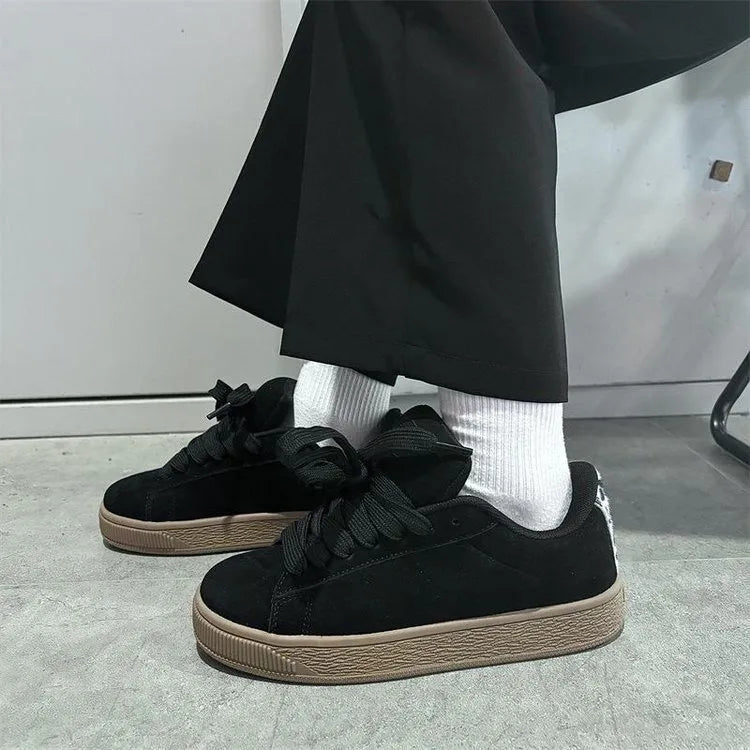 Black retro low-top sneakers with round toe and front lace-up closure on injection-moulded rubber sole