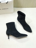 Black pointed toe women's ankle boot with a stiletto heel on a plain background.