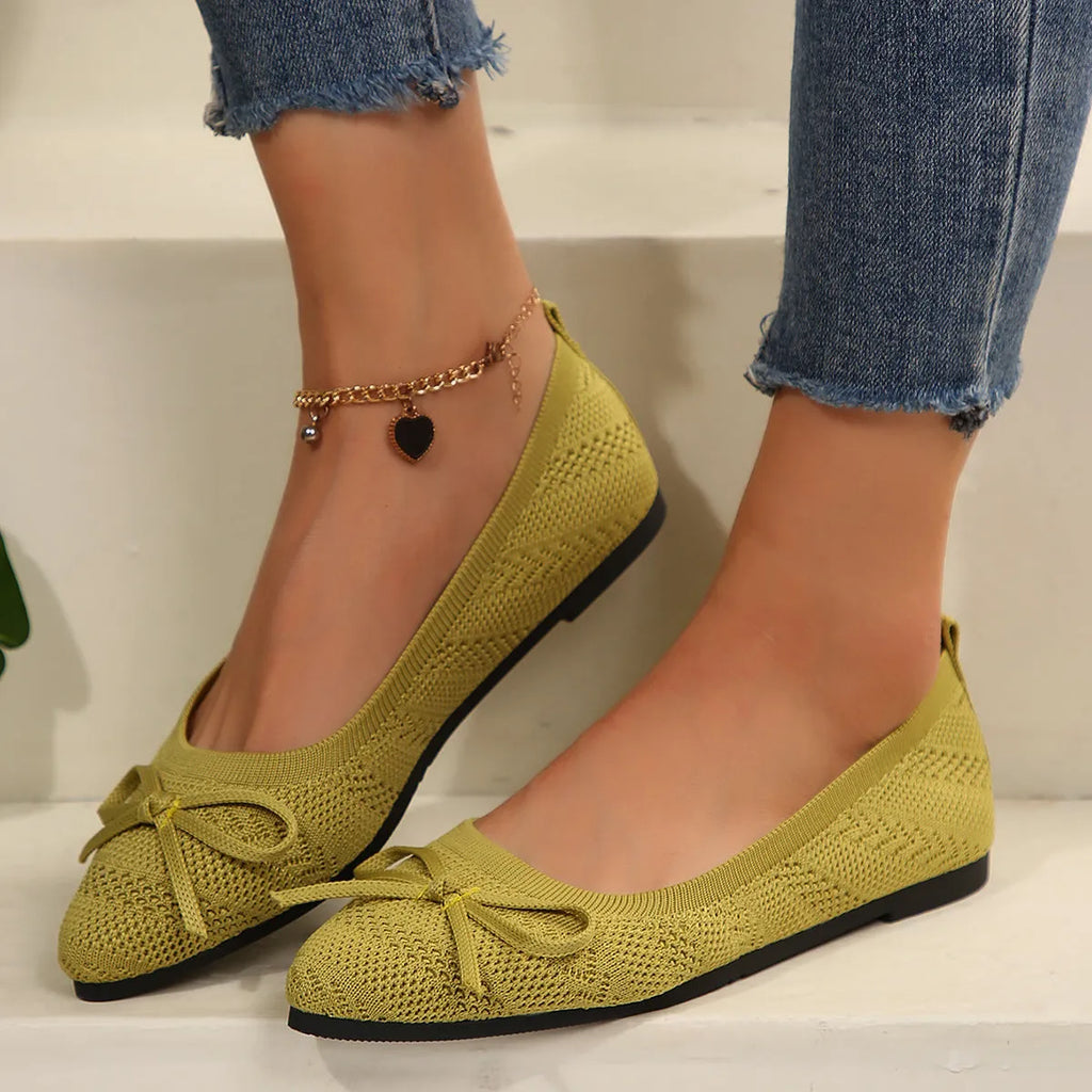 Women's blue knitted loafers with a bow detail and pointed toe on a flat rubber sole.
