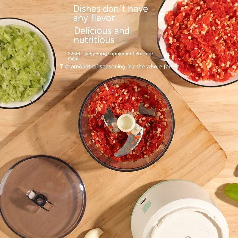 Mini electric meat grinder with transparent bowl in light green colour on a kitchen countertop.
