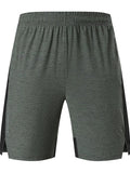 Man wearing mid-waist forest green spandex shorts, showcasing the casual fit and short length.