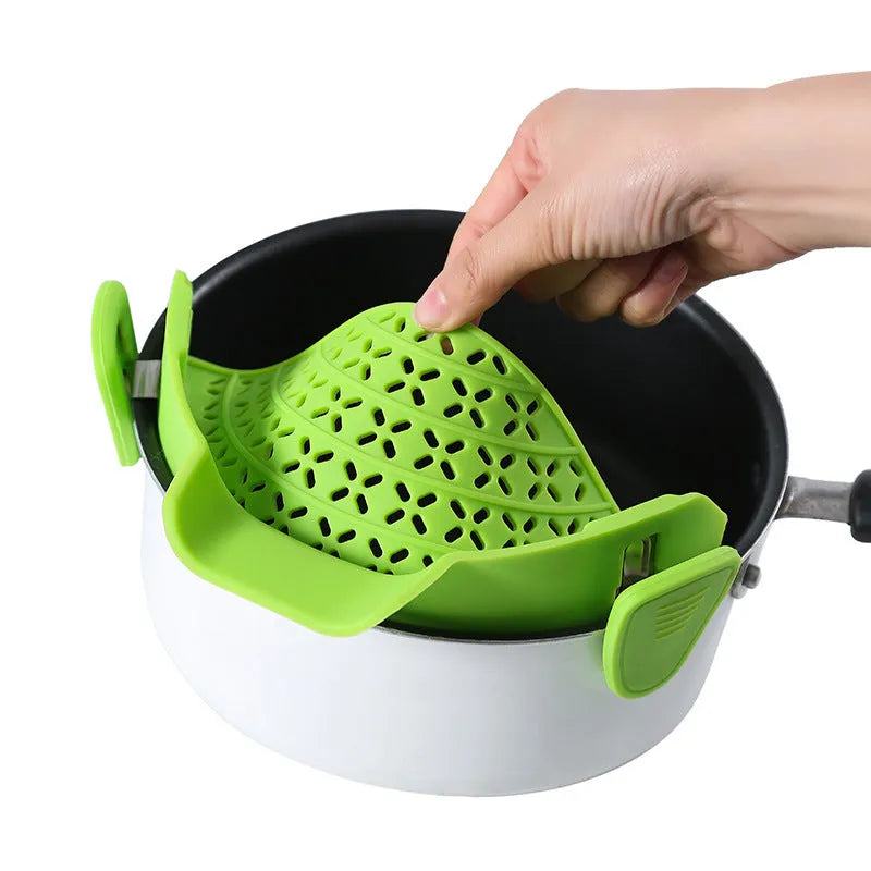 Green silicone pot rim drainer with stainless steel frame on a kitchen counter.