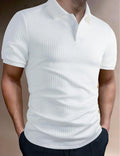 Man wearing a loose-fit striped polo shirt in a light blue colour, showing asymmetric detail and short sleeves.