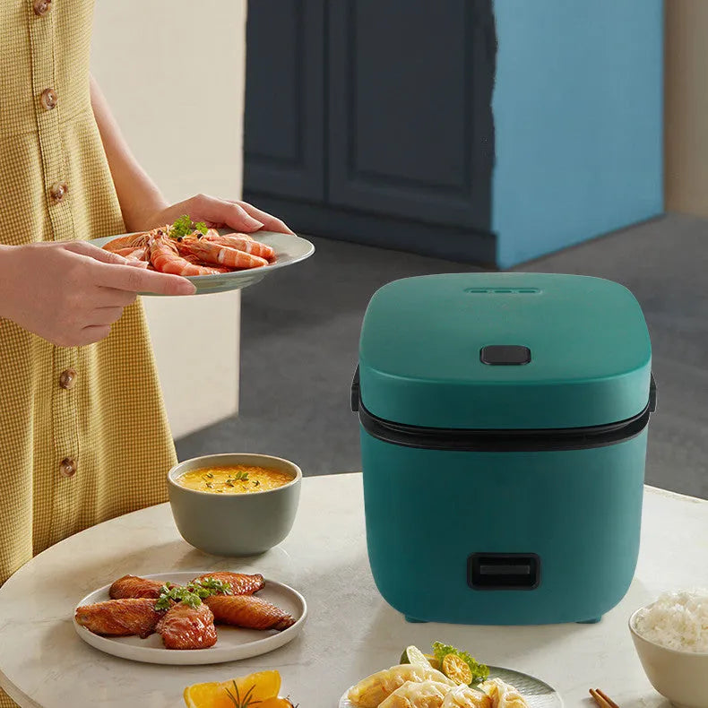 Green mini rice cooker 1.2L with steaming plate, rice spoon and measuring cup on countertop