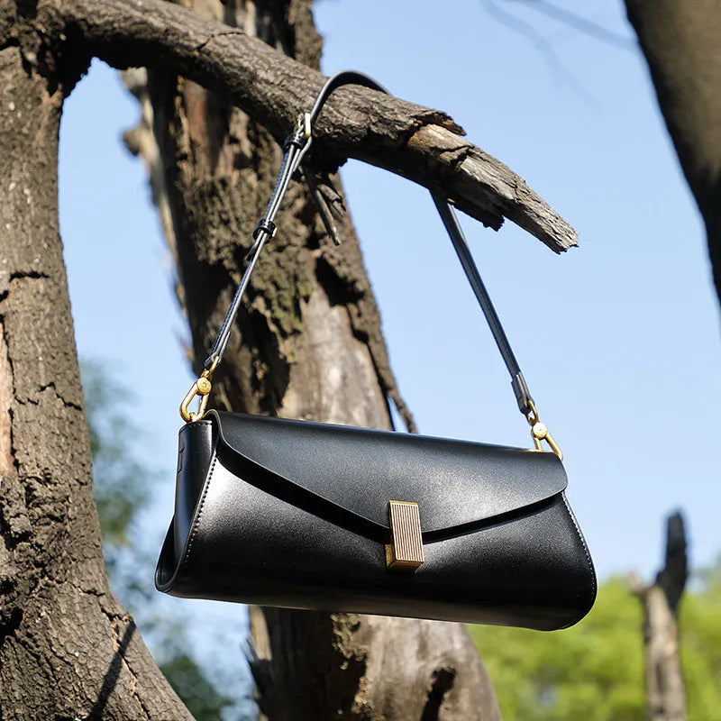 Cowhide leather cross-body shoulder bag in pillow shape with clamshell opening showing internal phone and document pockets