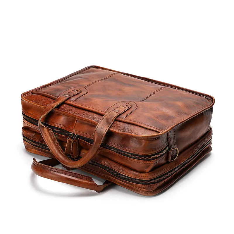 Brown vintage leather men's briefcase with soft handle, showing organised internal pockets for laptop and camera.