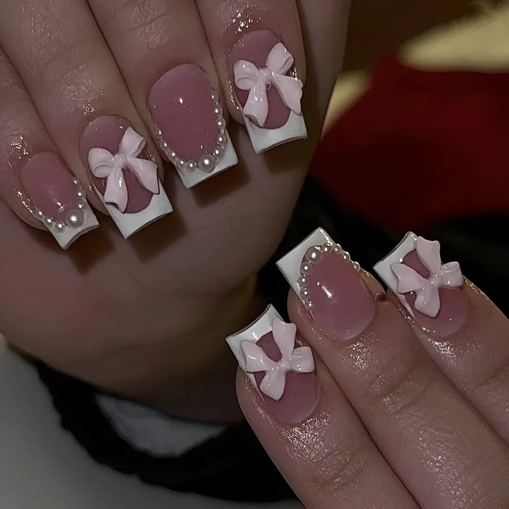 Set of 24 short, square, white-tipped French manicure false nails and a tube of nail glue on a pink background.