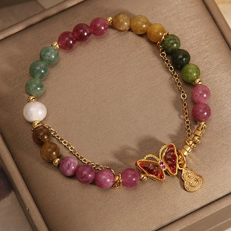 Close-up of a jade and tourmaline coloured agate bracelet with a butterfly-shaped gourd charm.