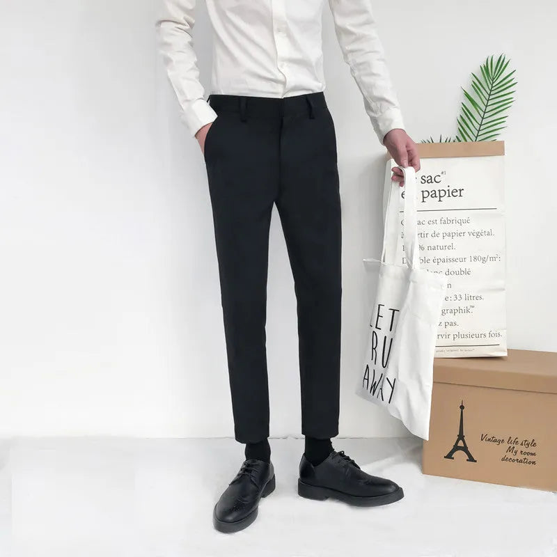 Man wearing black straight-leg cotton trousers with a drawstring waist, styled casually.