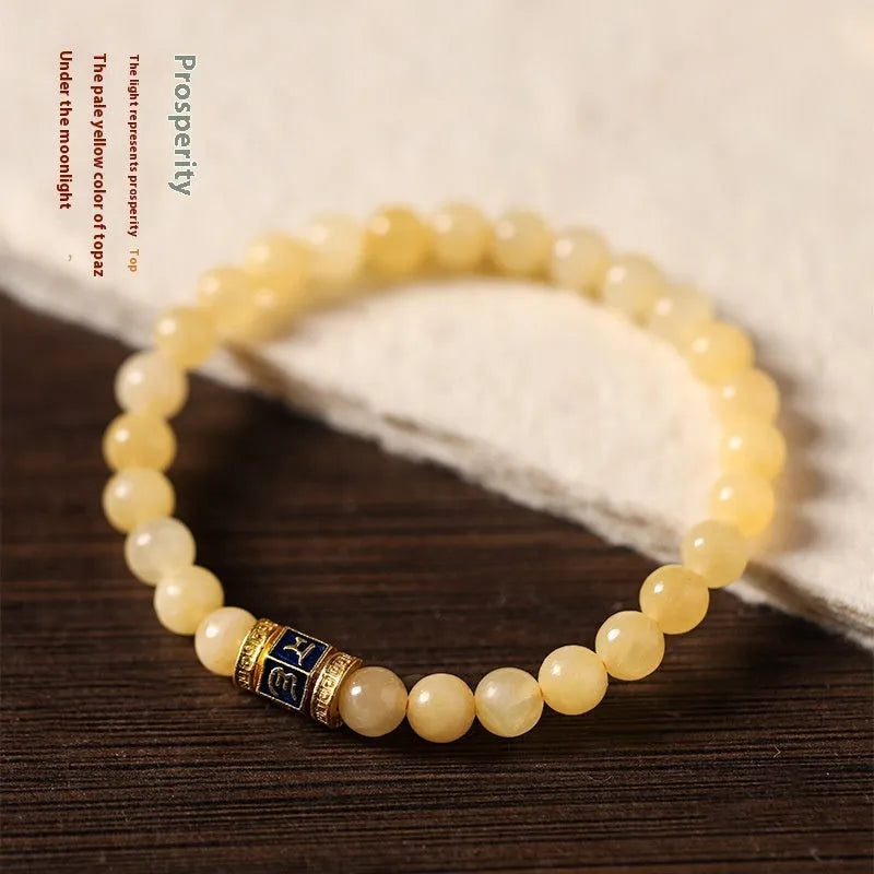 Women's hand-woven topaz bracelet with mantra barrel beads, square sugar beads, and fu charm in yellow jade