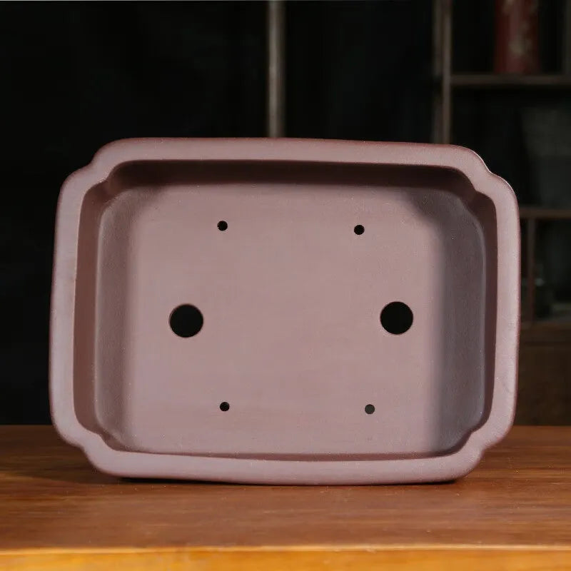 Rectangular antique purple sand bonsai pot with cut corners on a floor.