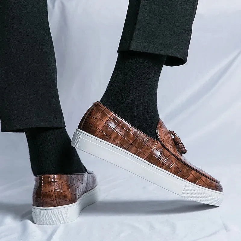 Men's black artificial leather sneaker with tassel detail on round toe, showing slip-on design.