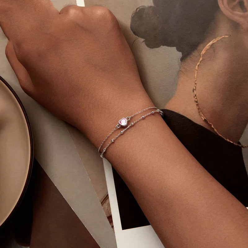 Close-up of a sweet girlish style sterling silver bracelet with a small heart pendant on an adjustable chain.