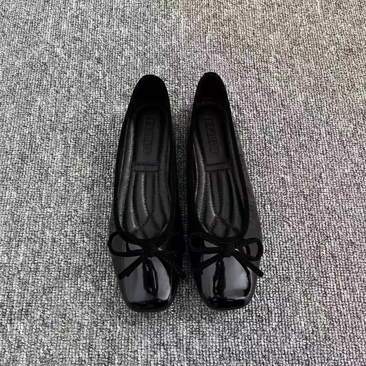 Pair of black patent leather Mary Jane flats with low heel and round toe