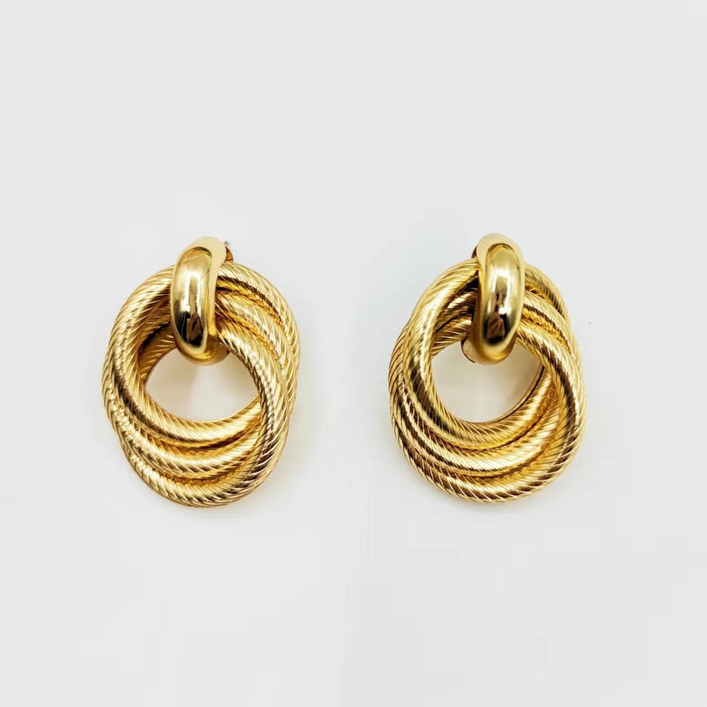 Gold metal geometric ring embossed twisted stud earrings on display