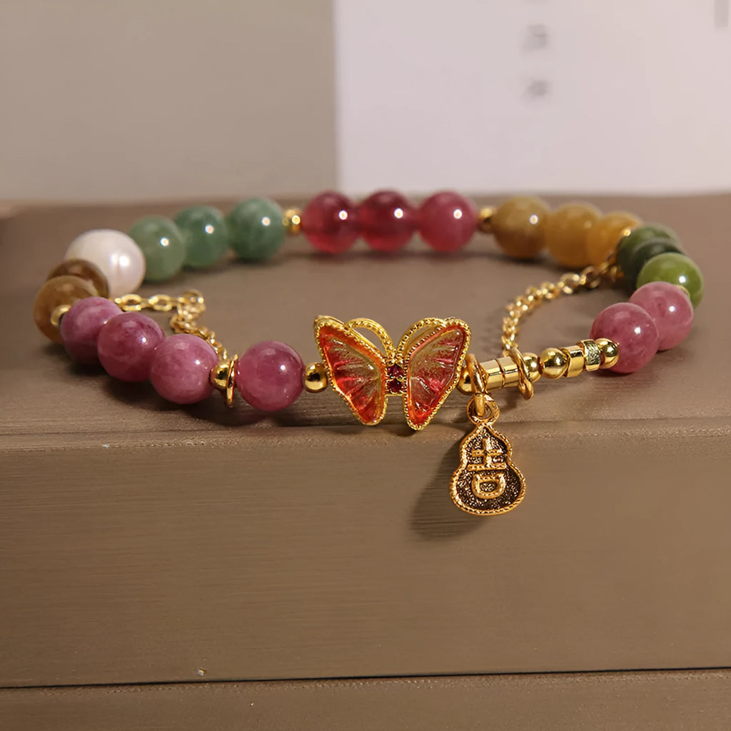 Close-up of a jade and tourmaline coloured agate bracelet with a butterfly-shaped gourd charm.