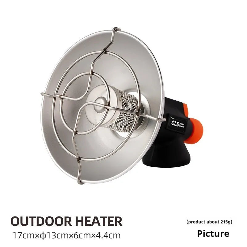 Black and orange mini portable camping stove with automatic ignition on a grassy outdoor surface.