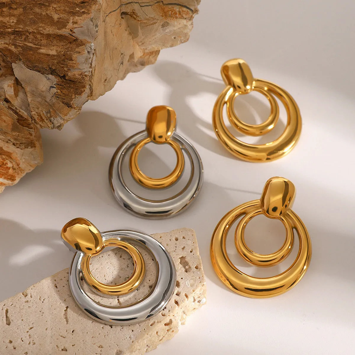 A pair of round, golden, hollow double layer stud earrings made from titanium steel with 18K gold electroplating.