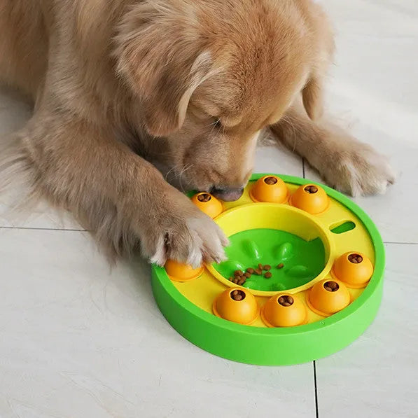 Square green dog puzzle toy with a central feeding well and a rotating turntable lid on a hard floor.
