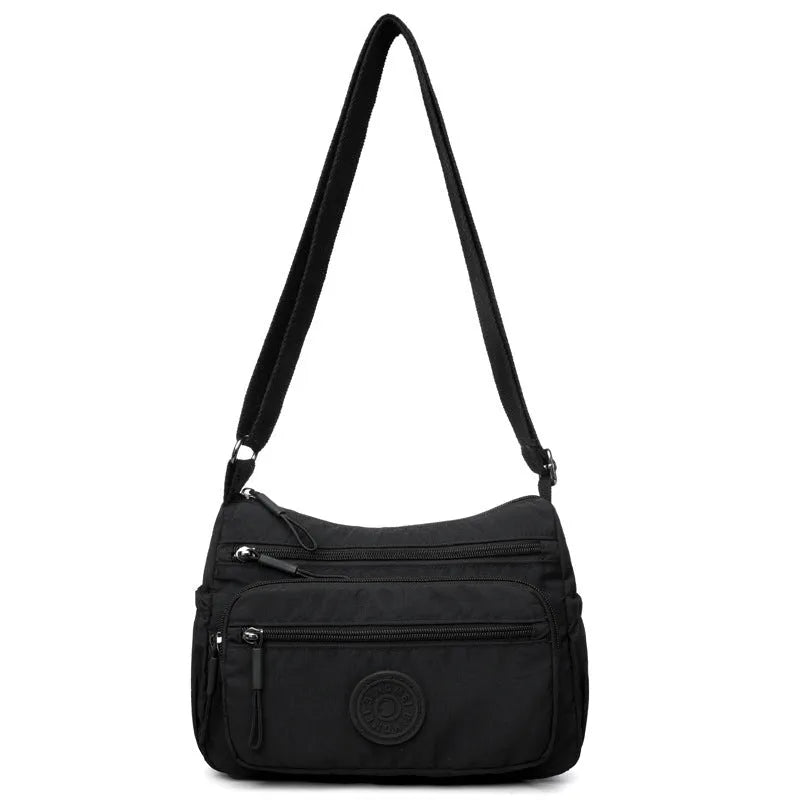 Soft water-repellent nylon crossbody bag in black with an outer pocket and zipped main compartment.