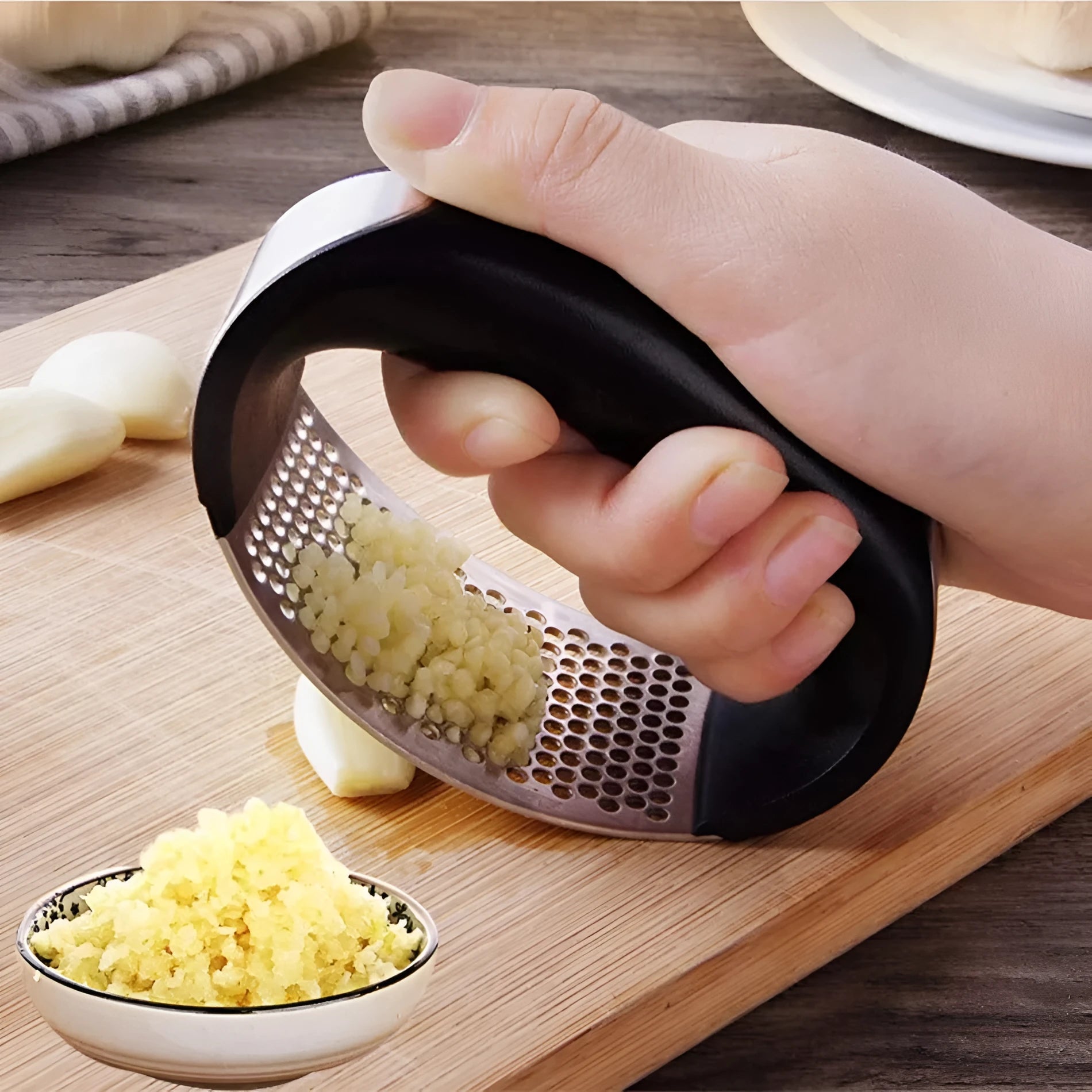 Stainless steel garlic press with coloured ergonomic handle on a kitchen counter.