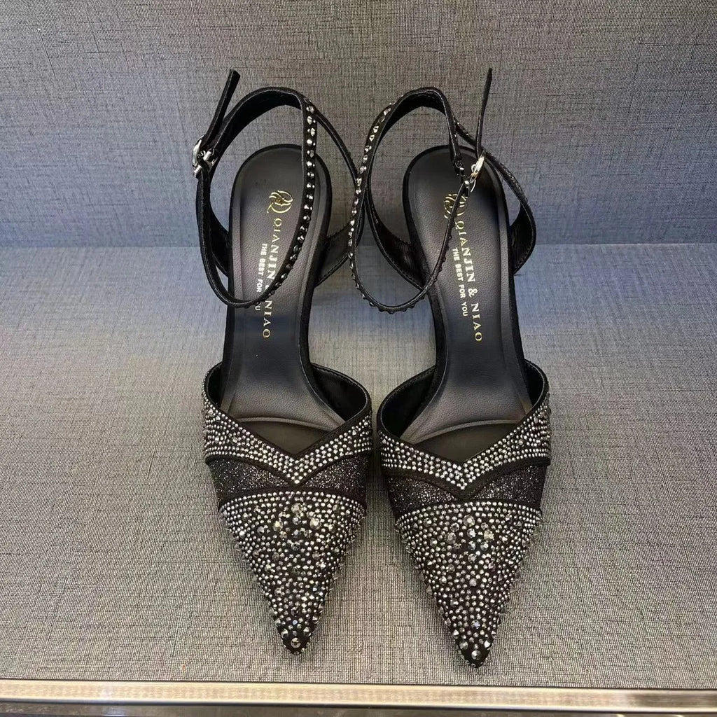 Women's black stiletto high heel with pointed toe and red sole, shown from the side.