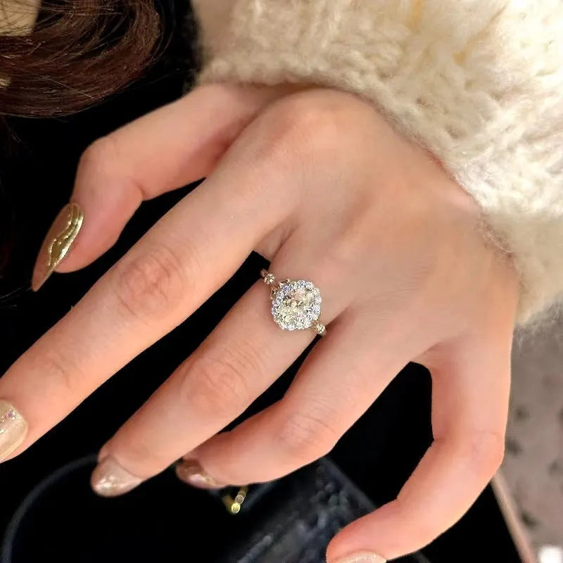Silver-colour geometric ellipse women's ring with central diamond on an adjustable band.