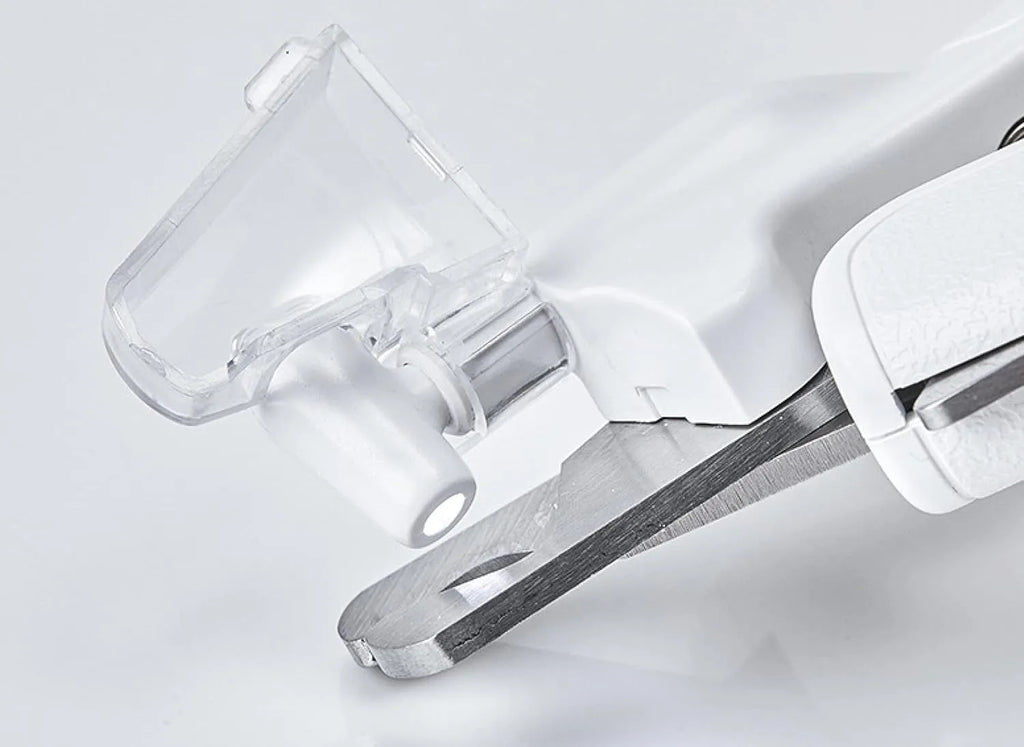 White pet nail clippers with LED light and transparent guard, shown with a separate nail file on a table.
