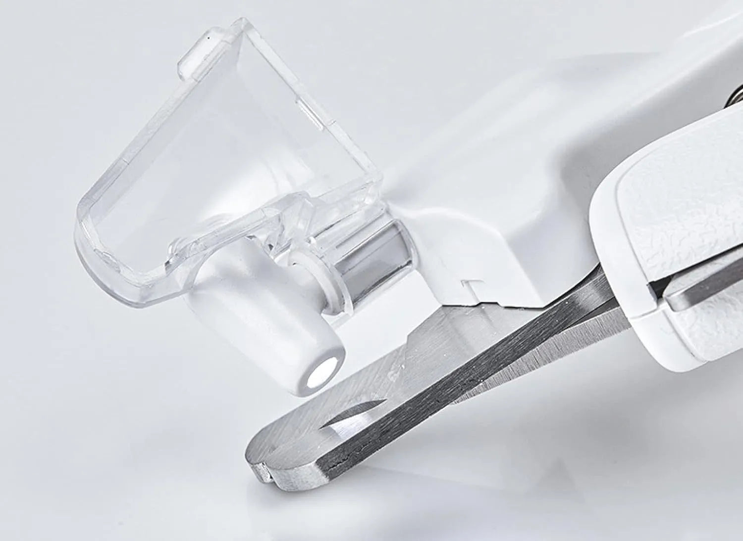 White pet nail clippers with LED light and transparent guard, shown with a separate nail file on a table.