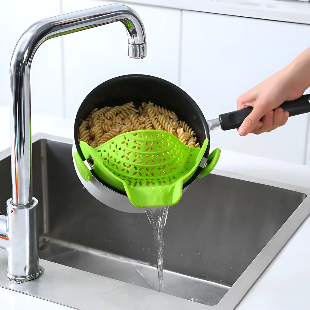 Green silicone pot rim drainer with stainless steel frame on a kitchen counter.