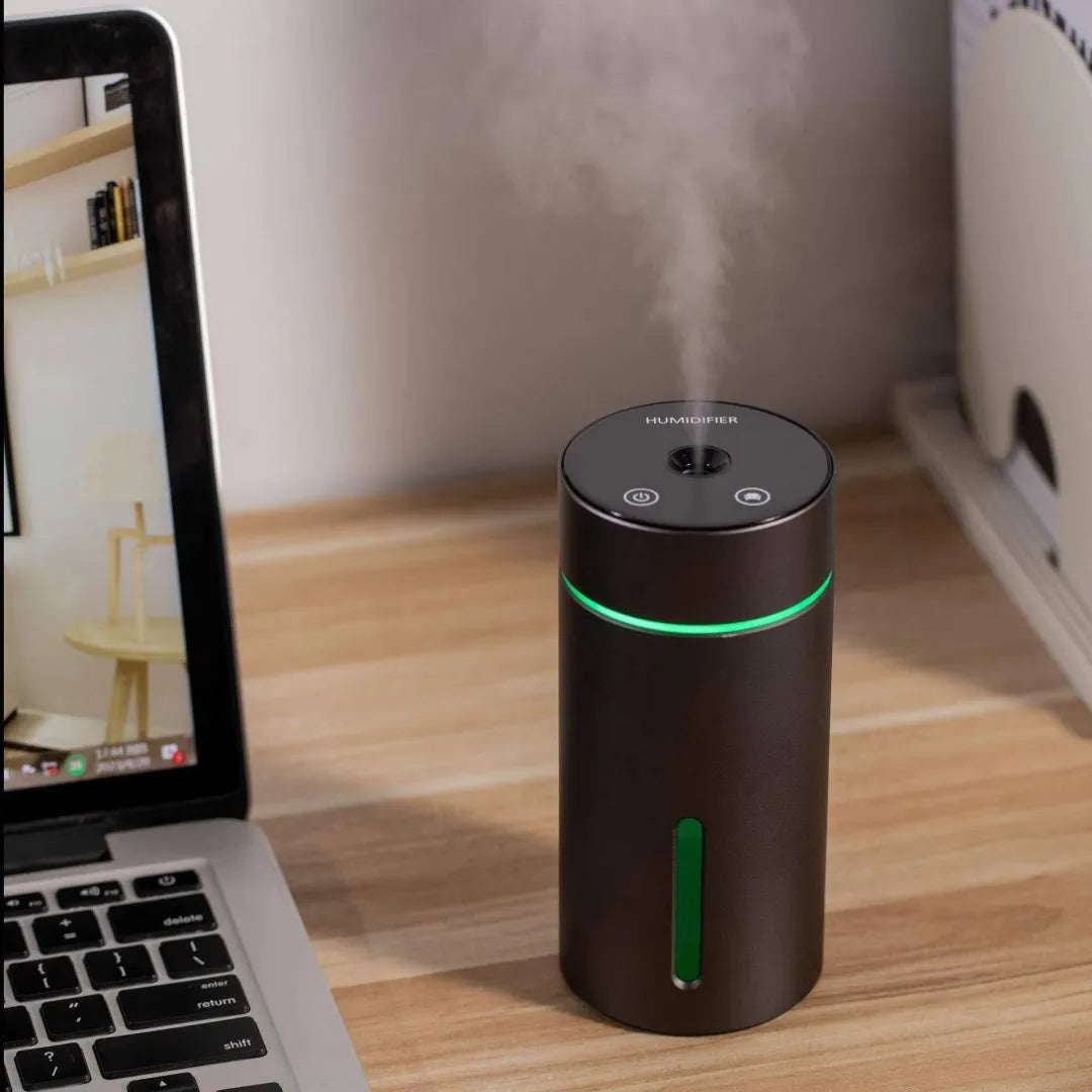 Black aluminium portable car humidifier and essential oil diffuser with USB cable on a desk.