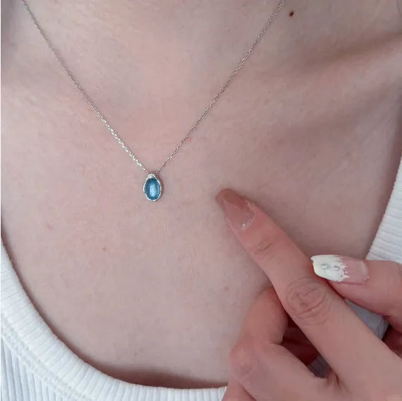 Close-up of a navy blue geometric water drop pendant on an adjustable silver-tone cross chain necklace.