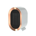 A compact black desktop ceramic fan heater with a mechanical control knob on a wooden desk.
