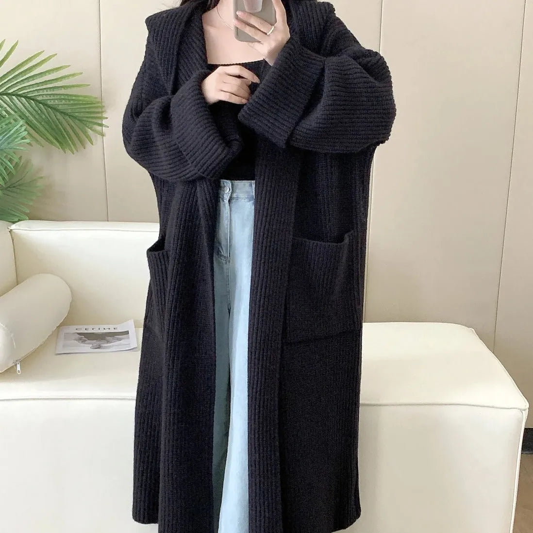 Woman wearing a long loose hooded cardigan coat in acrylic fabric, open as a cardigan.