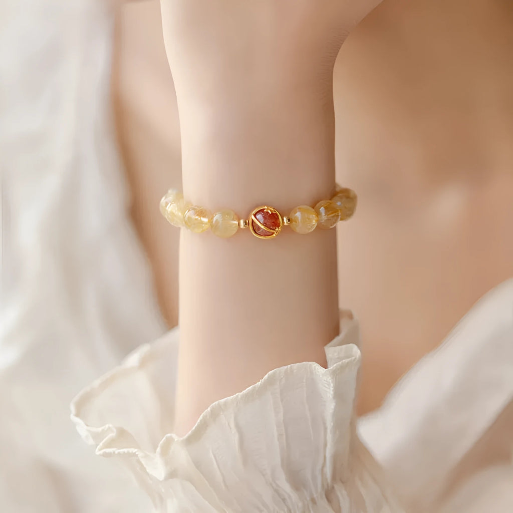 Citrine and gold rutilated quartz bracelet with diamond faceted beads on a wrist.
