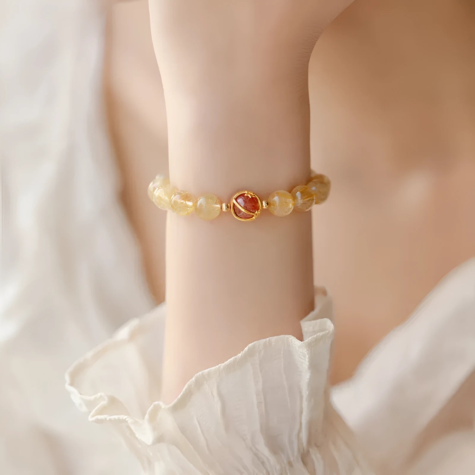 Citrine and gold rutilated quartz bracelet with diamond faceted beads on a wrist.