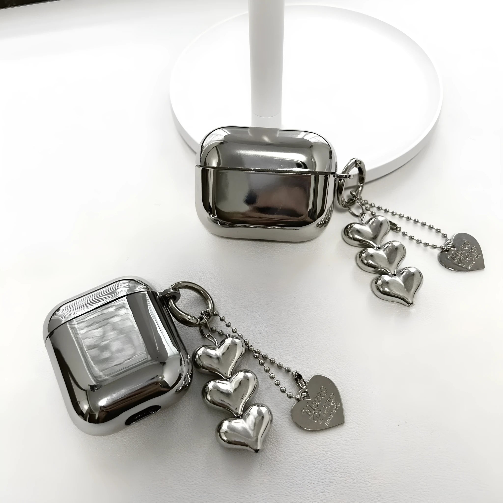Electroplated solid colour TPU headphone case with heart pendant charms and chain for Apple earbuds.