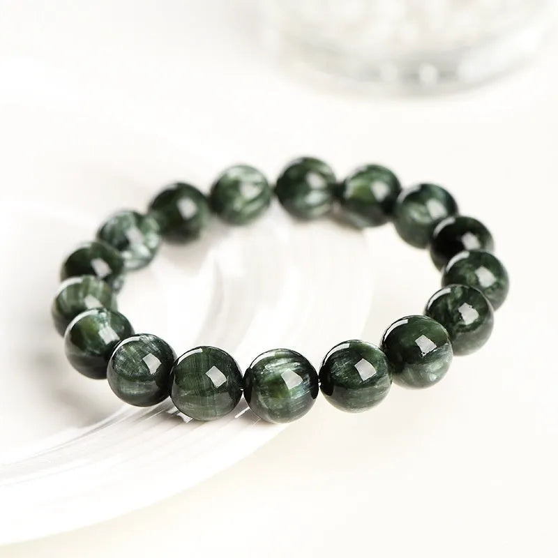 Close-up of a green dragon crystal bead bracelet with round geometry beads and a Ruyi charm.