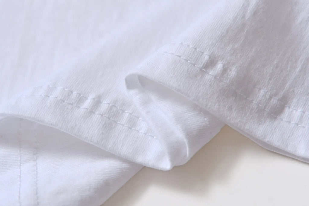 White cotton pullover overalls with short sleeves and a round neck, shown on a hanger.