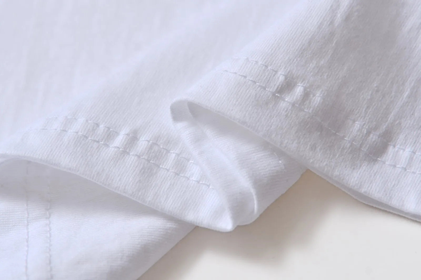 White cotton pullover overalls with short sleeves and a round neck, shown on a hanger.