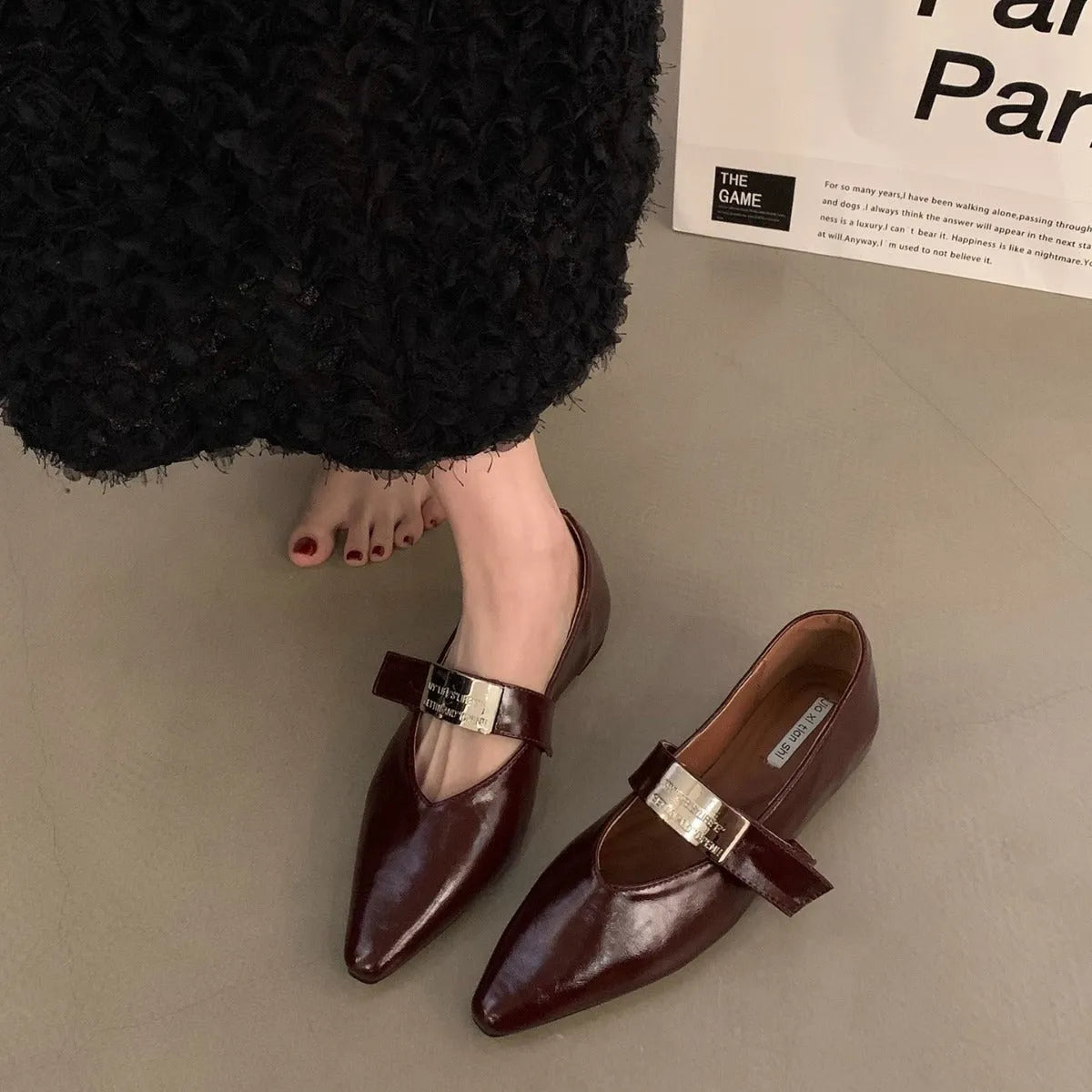 Women's black pointed toe Mary Jane buckle shoes with a low flat rubber sole.