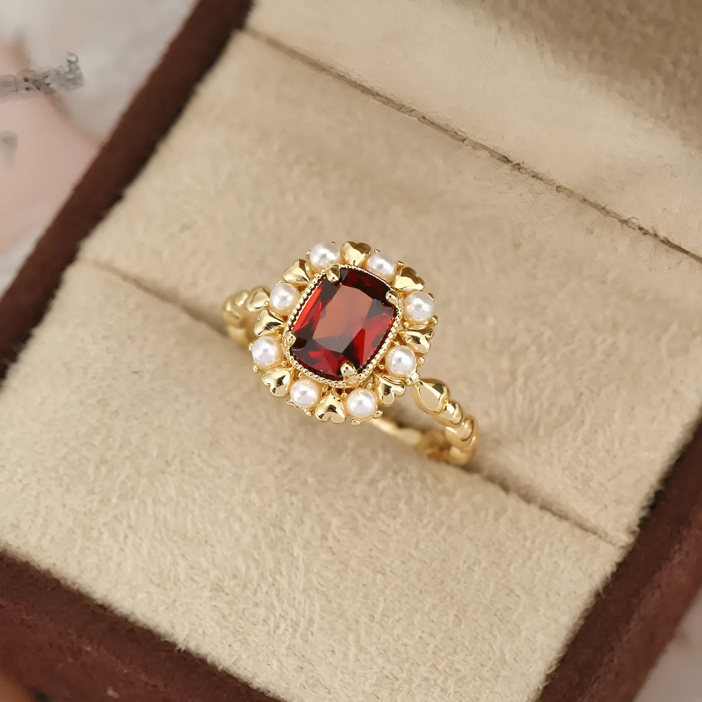 Gold electroplated ring with garnet red heart stone and geometric zircon setting.