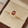 Gold electroplated ring with garnet red heart stone and geometric zircon setting.